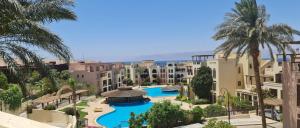 Al BurjFlat One Room Apartment Talabay Aqaba的享有带游泳池和棕榈树的度假村的景致
