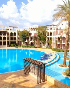 Al BurjFlat One Room Apartment Talabay Aqaba的棕榈树和建筑度假村内的游泳池