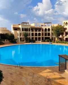 Al BurjFlat One Room Apartment Talabay Aqaba的大楼前的大型蓝色游泳池