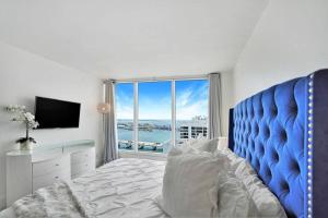 迈阿密Bay Watch Penthouse! Direct Water Views!的一间卧室设有蓝色的床和大窗户