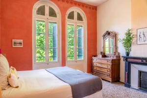 佩兹纳斯Ultimate Relaxation for Family or Group at Renowned Couvent des Ursulines, a Tranquil Escape in Historic Pézenas的一间卧室设有橙色的墙壁、一张床和一个壁炉