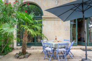 佩兹纳斯Ultimate Relaxation for Family or Group at Renowned Couvent des Ursulines, a Tranquil Escape in Historic Pézenas的一张带椅子的蓝色桌子和一把雨伞