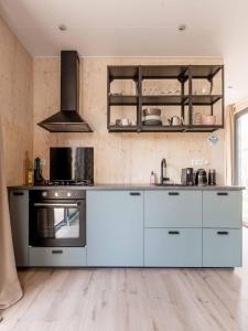 宁斯佩特Ultiem ontspannen in compleet ingericht tiny house in bosrijke omgeving的厨房配有白色橱柜和炉灶。