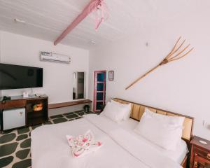 布什格尔The Luxe Pushkar By Namli Hotels的卧室配有带白色床单的床铺和平面电视。