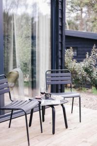 宁斯佩特Ultiem ontspannen in compleet ingericht tiny house in bosrijke omgeving的两把椅子和一张桌子,上面放着一杯葡萄酒