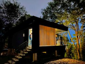 比亚维森西奥Itawa Luxury Glamping & Ecoparque turísticos的一间黑色的小房子,一个站在窗户上的人