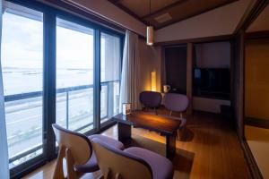 热海Taiseikan的配有椅子和桌子以及大窗户的房间