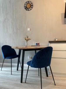 格利维采Apartamet Poezji A04 Blue的餐桌、两把椅子和墙上的时钟