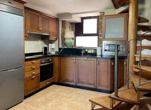 CoveloEspectacular casa en Covelo的厨房配有木制橱柜和不锈钢冰箱。