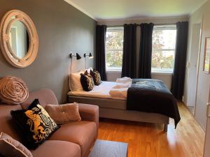 诺托登Brattrein Hotell - Unike Hoteller的一间卧室配有一张床、一张沙发和一面镜子