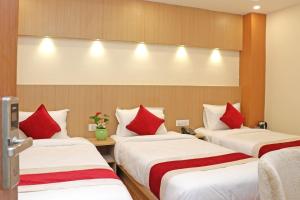 加德满都Hotel Nilakantha Pvt. Ltd的配有红色枕头的酒店客房内的三张床