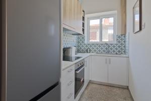 雅典Vivid Stays Petralona的厨房配有白色橱柜和窗户。