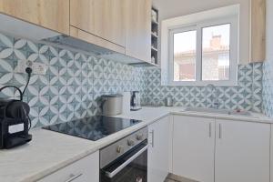 雅典Vivid Stays Petralona的厨房配有白色橱柜和几何瓷砖墙
