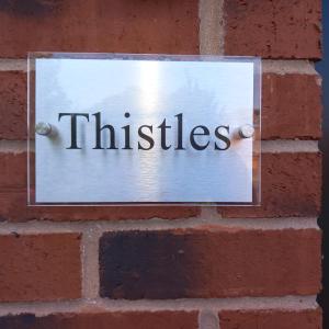 Thistles -Private Entrance Studio的砖墙上的一个标志,上面有口哨