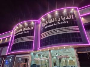 Al Qunfudhahالديار الفاخرة للشقق المخدومة的上面有紫色灯的建筑