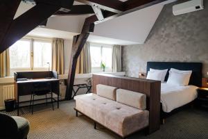 沃尔堡Central Park Voorburg - Relais & Chateaux的卧室配有床、书桌和钢琴