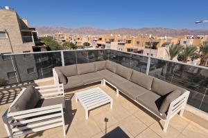 埃拉特YalaRent Villa Dolina with private pool的阳台的天井配有沙发和椅子