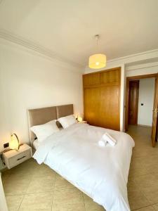 拉巴特Appartement au cœur de Rabat的卧室配有一张白色大床和木制床头板