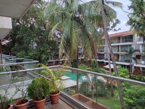 卡兰古特Goan Fiesta 1BHK Pool View at Eternal Wave CALANGUTE的棕榈树公寓阳台和游泳池