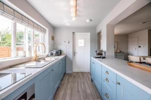 AldringhamWonderful cottage with sun-filled terrace的一间设有蓝色橱柜和窗户的大厨房