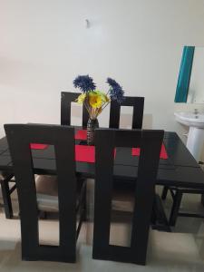 纳库鲁Jacky's Milimani suites的一张带两把椅子的黑色餐桌和花瓶