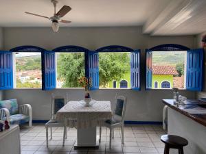 伦索伊斯Pousada Lavramor的一间设有桌子和蓝色窗户的用餐室