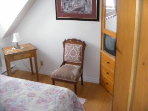 圣加布里尔德瓦尔卡捷Auberge La Seigneurie Valcartier的一间卧室配有一张床、一把椅子和电视。