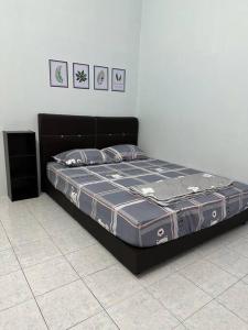 大港Guan Homestay Sungai Besar 大港民宿的一张位于黑床架的房间的床位