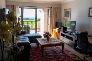 莫塞尔湾Fairways Apartment Mossel Bay Golf Estate的带沙发、电视和桌子的客厅