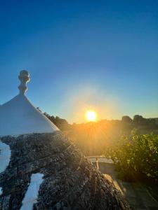 奥斯图尼Piccolo Trullo Ostunese Le Jardin de Sophie'的享有日落美景,设有石墙