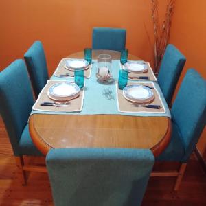 阿韦利亚内达Iris Departamento的一张带蓝色椅子的桌子和一张带盘子和盘子的桌子