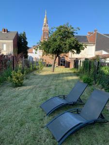 阿尔贝COTTAGE DU PARC的两把椅子放在一个院子内,后面有一个钟楼