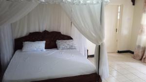 埃尔多雷特Trans-Africa equator hotel的卧室配有带白色窗帘的天蓬床