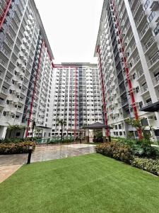 马尼拉2BR SMDC Bloom Residences Near NAIA Wi-fi +Netflix的一座大型公寓楼,前面设有草坪