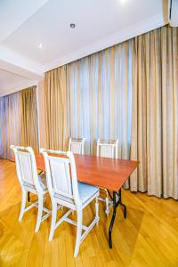 巴库Deluxe Apartment 142/43的一间带木桌和白色椅子的用餐室