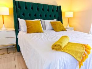 贝拉贝拉Genesis Guesthouze的一张带黄色枕头和绿色床头板的白色床