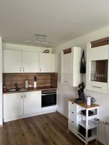 蒂蒂湖-新城Ferienwohnung Traumwerk Titisee的厨房配有白色橱柜和木桌