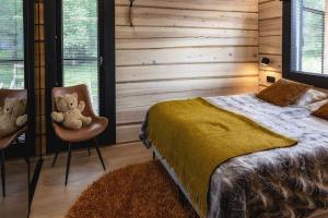 伊纳利Upea Villa Lapin Kulta hirsihuvila Inarijärven rannalla的一间卧室配有一张床,两只泰迪熊坐在椅子上