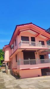 NuvemThe Sea Breeze的粉红色的房子,旁边设有阳台