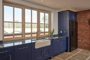 BucknellA true British country escape!的厨房配有蓝色橱柜、水槽和窗户。