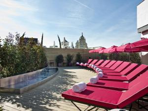 马德里The Principal Madrid, Small Luxury Hotels的庭院里一排带遮阳伞的红色长椅