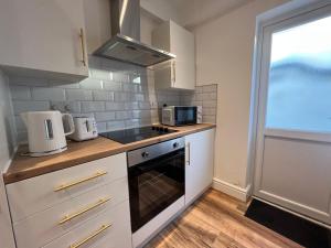 利物浦Liverpool Cherry House - 4 Bedrooms的厨房配有白色橱柜、炉灶和窗户。