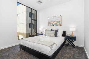 Port AdelaideUrban Rest Port Adelaide Apartments的一间卧室设有一张大床和一个窗户。