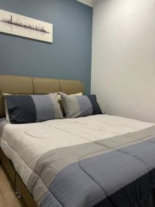 古晋Spacious Home @ Kuching City Ctr的卧室内的一张床铺,卧室内有蓝色的墙壁
