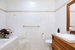 尼尔森湾Arabella的浴室配有白色浴缸、水槽和椅子
