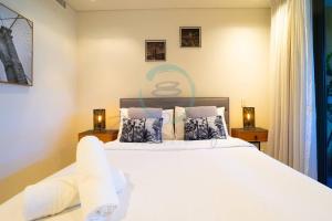 达尔文Zen Seaside 1BR Waterfront Apt的一间卧室配有一张带两盏灯的大型白色床。