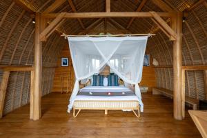 蓝梦岛Morin Resort的一间位于稻草小屋的卧室,配有一张天蓬床