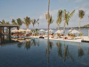 吉利美诺BASK Gili Meno的海滩上带棕榈树和遮阳伞的游泳池