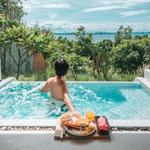 格兰岛Myth Koh Larn resort bar and bistro的游泳池里的男孩,带上一盘食物