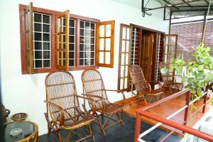Fort KochiWalton's Homestay, Fort Cochin的门廊配有椅子、桌子和窗户